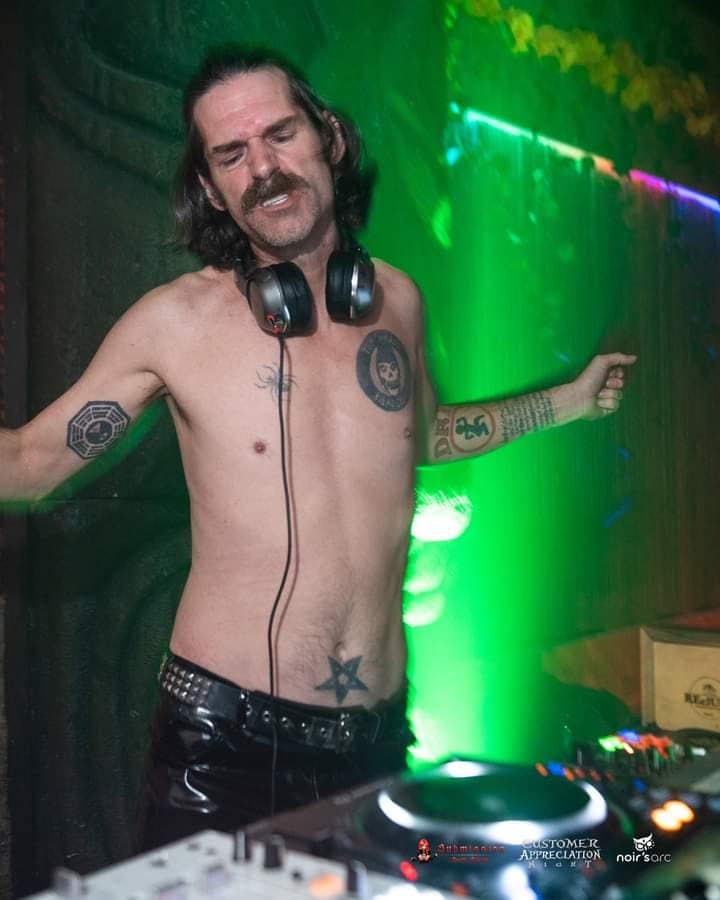 MR. SATAN wearing headphones under green light.