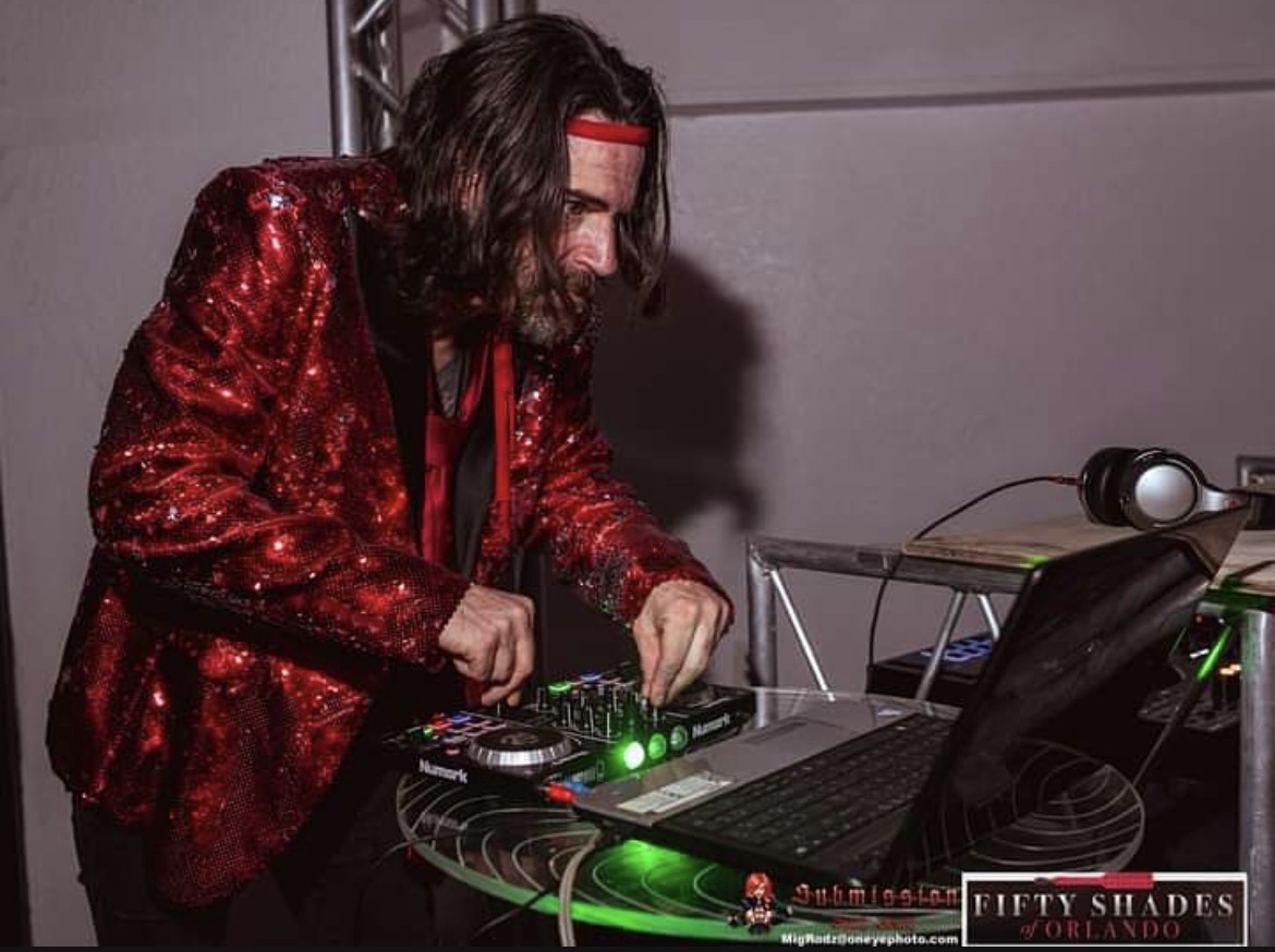 MR. SATAN DJing in a red jacket.